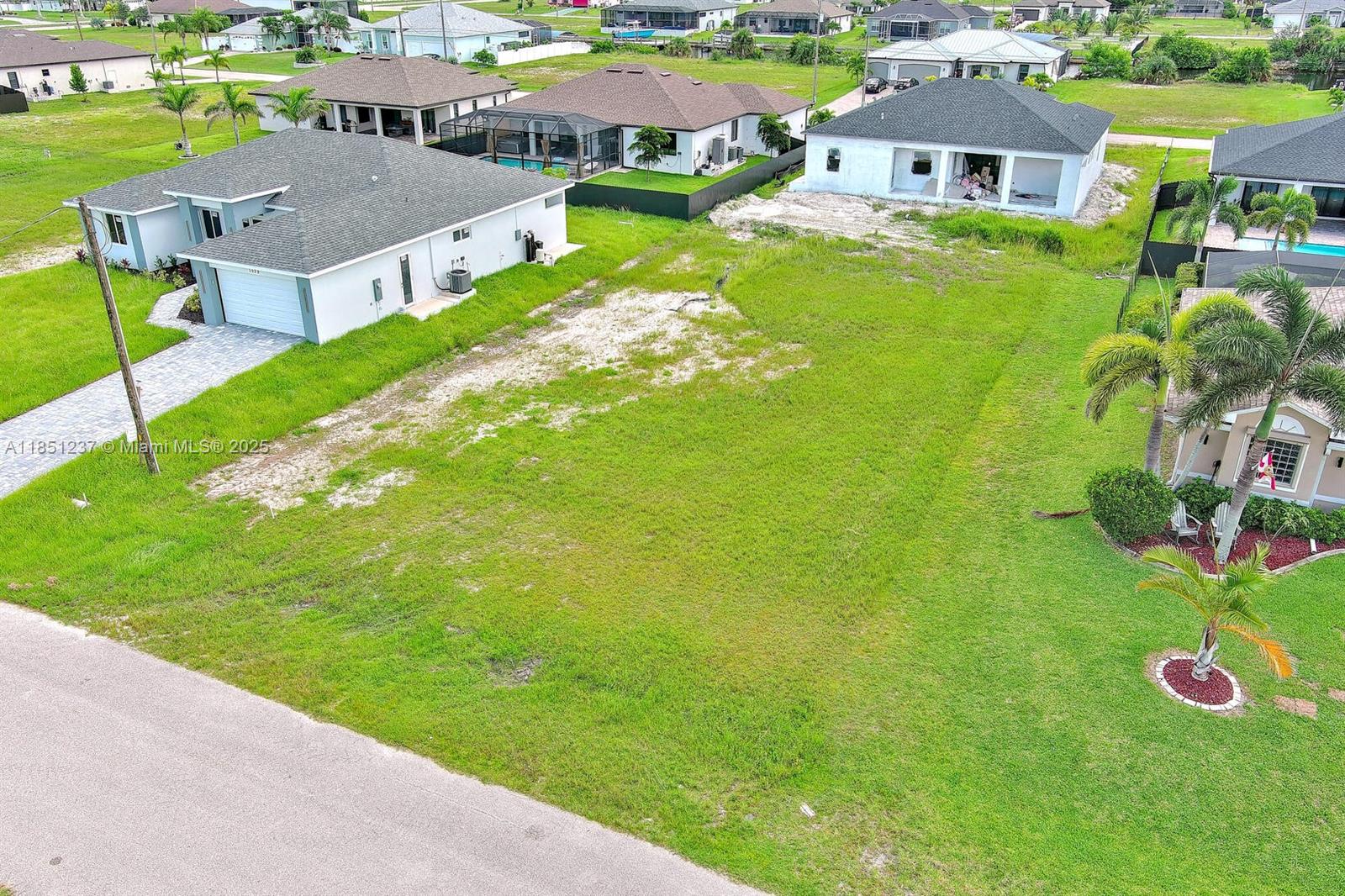 An aerial view shows a vacant residential lot situated between two single-family homes — 1025 NW 35th Place, Cape Coral FL 33993, CAPE CORAL, FL