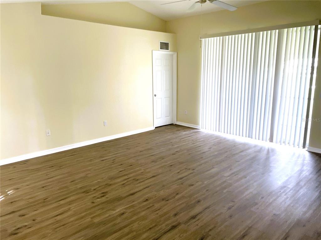 An empty room with light-colored walls, wood-look flooring, a ceiling fan, and vertical blinds — 2498 MARGARET LANE, NORTH PORT, FL