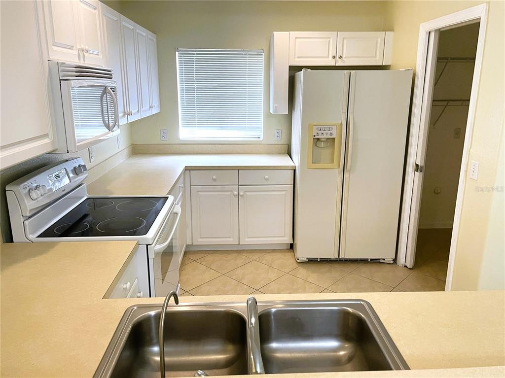 A kitchen features white cabinets, white appliances, a double sink, and tile flooring — 2498 MARGARET LANE, NORTH PORT, FL