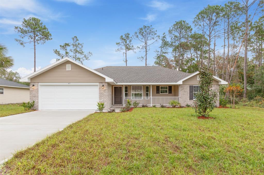A single-story house with a beige siding gable, brick facade, and a white garage door — 48 PHEASANT DRIVE, PALM COAST, FL