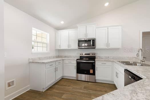 A modern kitchen features white cabinets, stainless steel appliances, and light-colored countertops — 48 PHEASANT DRIVE, PALM COAST, FL