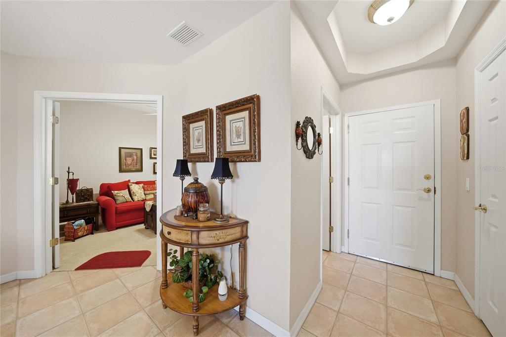 An entryway features tile flooring, a round wooden console table, and a view into a room — 255 WEST END DRIVE UNIT 3306, PUNTA GORDA, FL