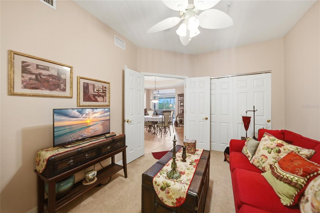 A carpeted room features a red sofa, a television on a wooden console, and double doors — 255 WEST END DRIVE UNIT 3306, PUNTA GORDA, FL