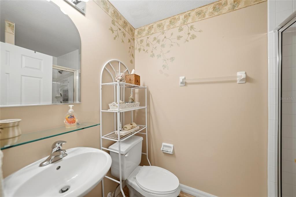 A bathroom features a pedestal sink, a toilet with a metal storage rack, and beige walls — 255 WEST END DRIVE UNIT 3306, PUNTA GORDA, FL