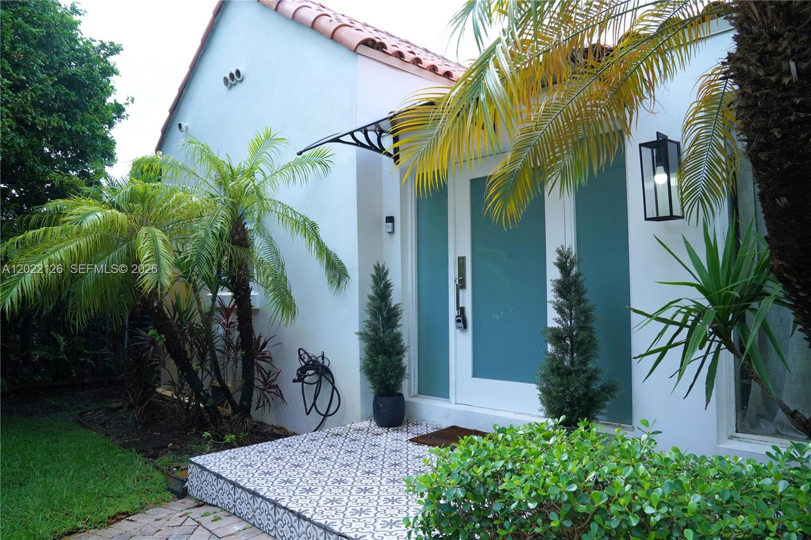 The exterior of a house features a tiled porch, a modern glass door, and palm trees — 2338 SW 11th St # 2338, Miami FL 33135, MIAMI, FL