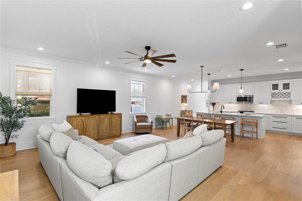 An open-concept living room and kitchen feature light wood floors, white cabinetry, and a sectional — 213 W ELM STREET, TAMPA, FL