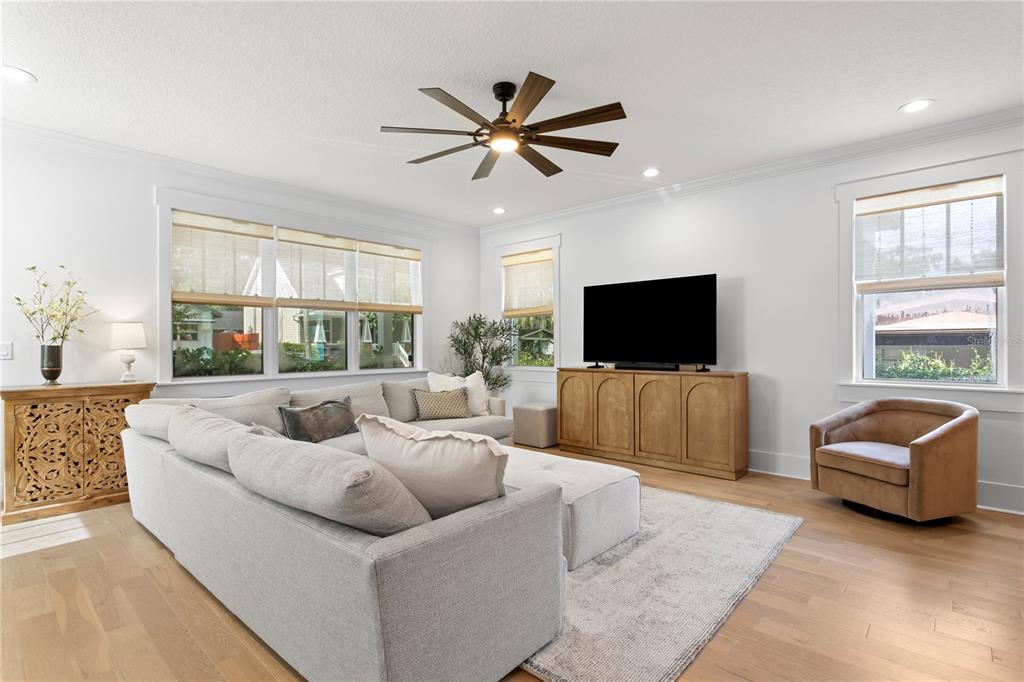 A living room features a large sectional sofa, a television on a wooden console, and a ceiling fan — 213 W ELM STREET, TAMPA, FL