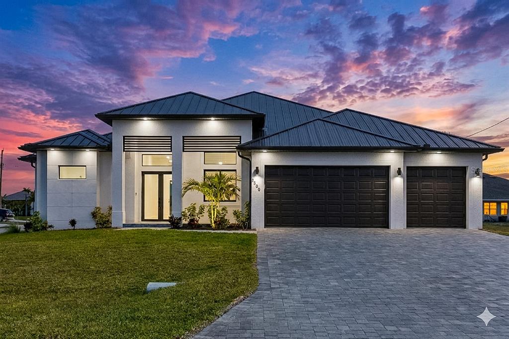 A modern single-story house with a metal roof, white stucco exterior, and three-car garage — 3300 NW 1ST TERRACE, CAPE CORAL, FL