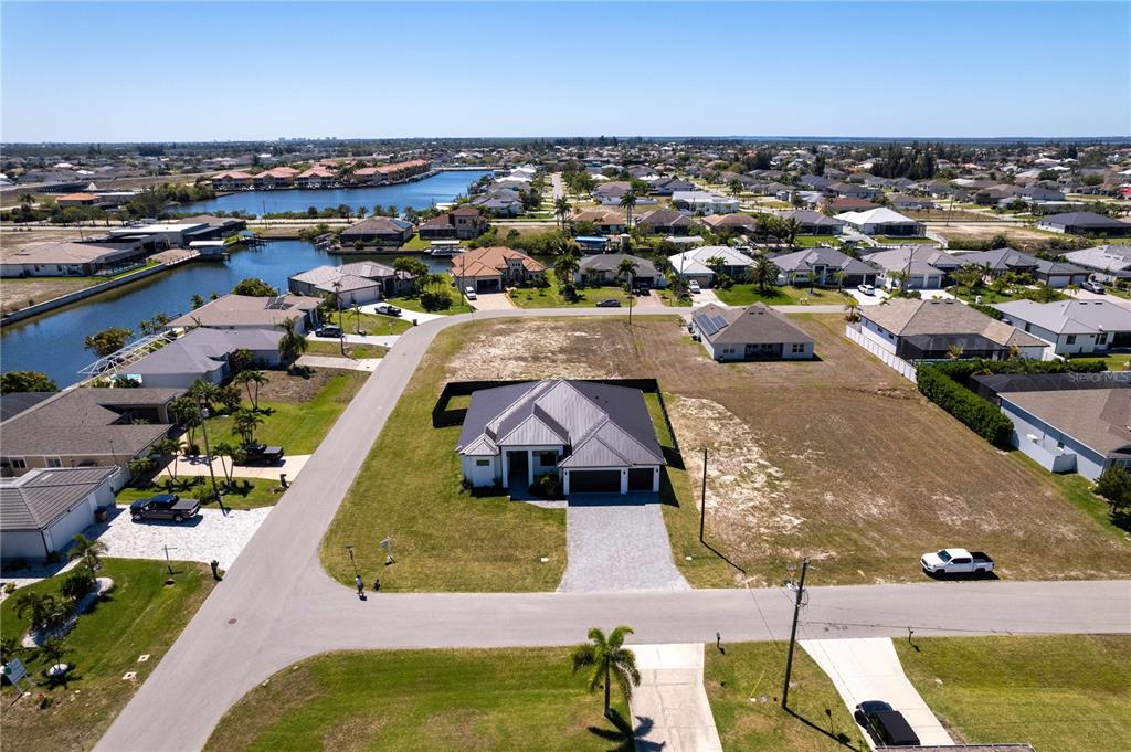 An aerial view shows a single-story house with a gray roof on a corner lot — 3300 NW 1ST TERRACE, CAPE CORAL, FL