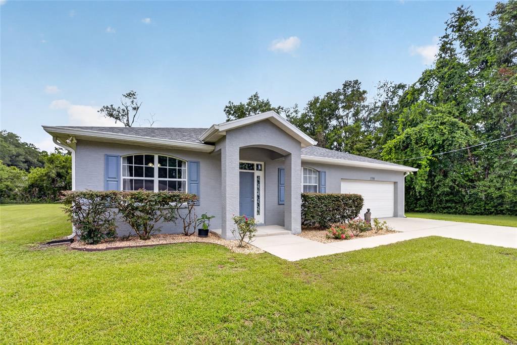 A single-story gray house with blue shutters, a front porch, and an attached garage — 3788 SE 133RD PLACE, BELLEVIEW, FL