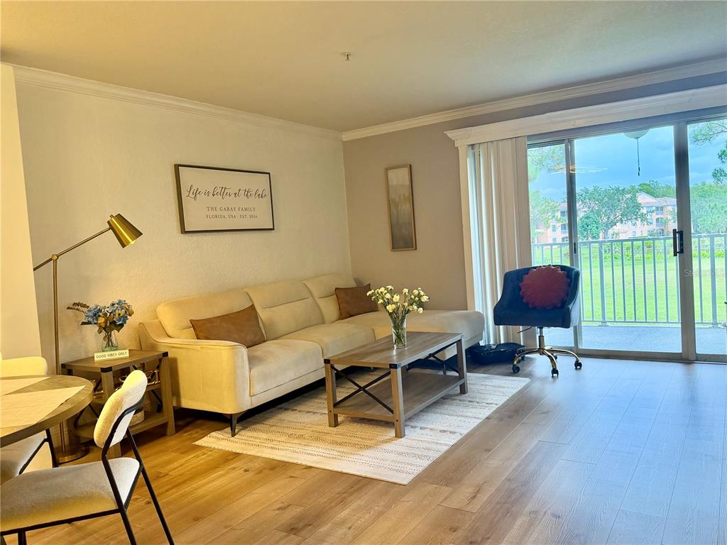 A living room features a beige sofa, a wooden coffee table, and a sliding glass door — 14049 FAIRWAY ISLAND DRIVE UNIT 124, ORLANDO, FL