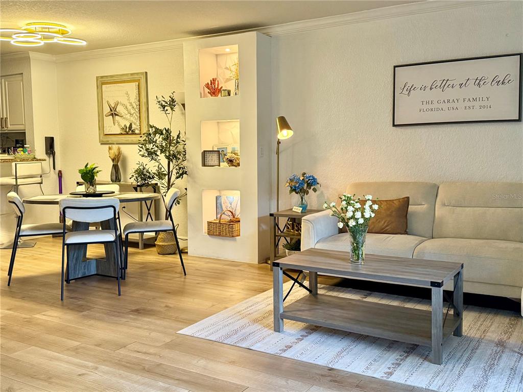 A living room and dining area feature light wood flooring, a beige sofa, and built-in shelving — 14049 FAIRWAY ISLAND DRIVE UNIT 124, ORLANDO, FL
