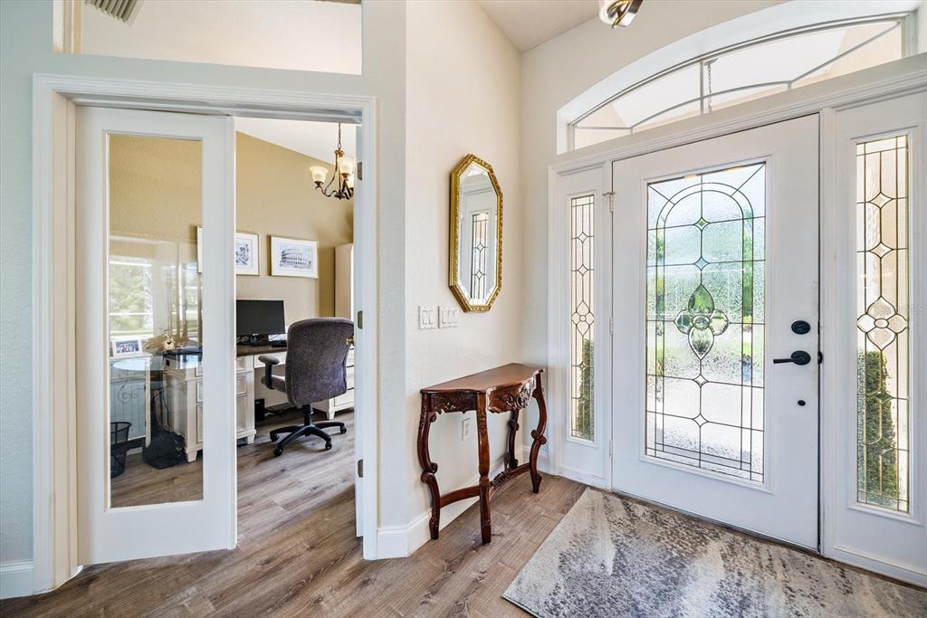 A bright entryway features a wood-look floor, a glass-paneled front door, and a home office — 11909 SUMMER MEADOW DRIVE, LAKEWOOD RANCH, FL