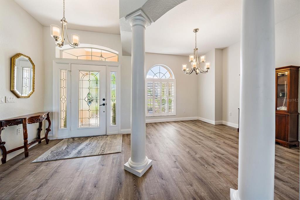 An entryway with wood-look flooring, white columns, a chandelier, and a front door with sidelights — 11909 SUMMER MEADOW DRIVE, LAKEWOOD RANCH, FL