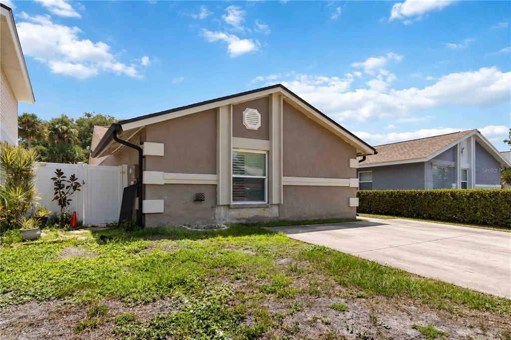 A tan, single-story house with a concrete driveway and a white privacy fence — 10327 PARKCREST DRIVE, TAMPA, FL