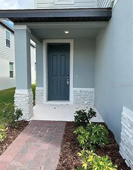 A front entryway features a dark blue door, stone accents, and a brick walkway — 501 SUN WARBLER WAY, ST CLOUD, FL