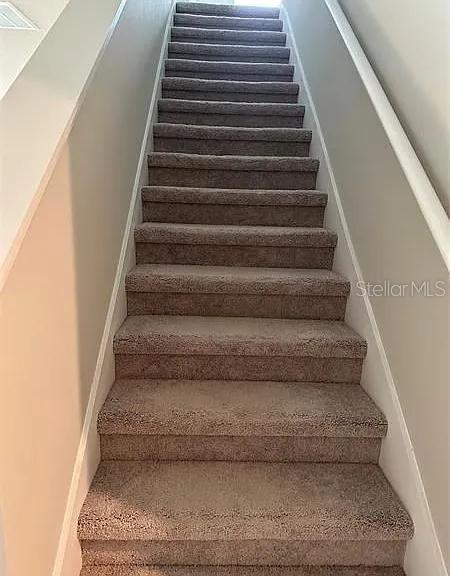 A straight staircase with brown carpeted steps leads upward between two plain white walls — 501 SUN WARBLER WAY, ST CLOUD, FL