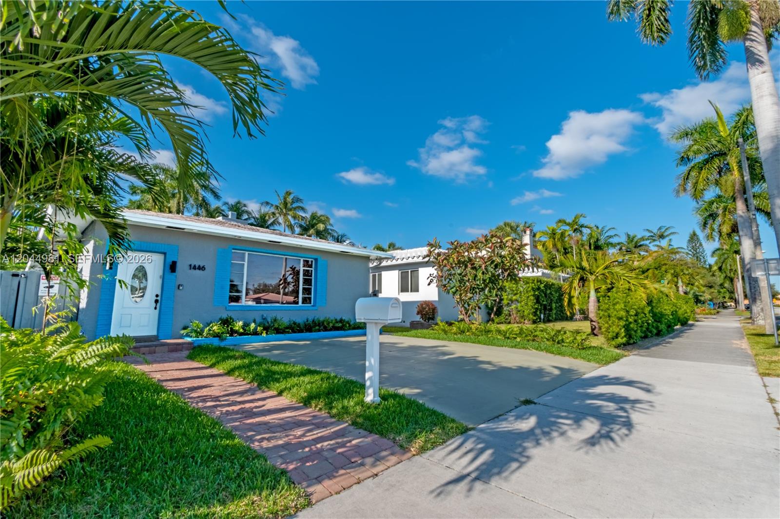A single-story gray house with bright blue trim and a brick walkway under palm trees — 1446 Hollywood Blvd, Hollywood FL 33020, HOLLYWOOD, FL