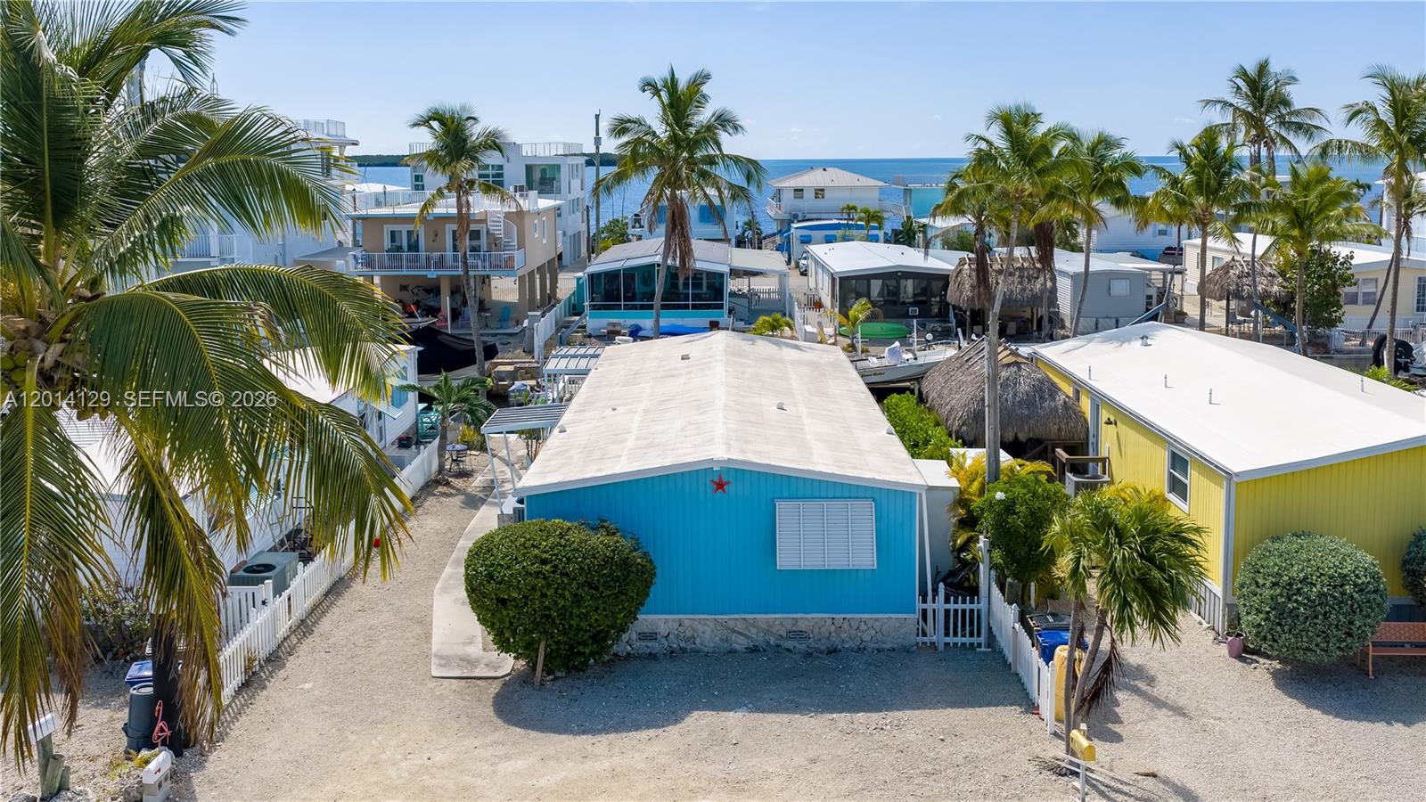 An aerial view shows a bright blue mobile home with a white roof and palm trees — 205 Humpty Dumpty Dr, Key Largo FL 33037, KEY LARGO, FL