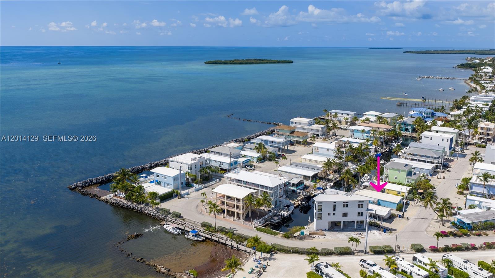 An aerial view shows a coastal neighborhood with houses, a canal, and a pink arrow — 205 Humpty Dumpty Dr, Key Largo FL 33037, KEY LARGO, FL