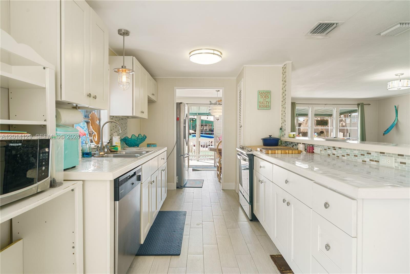 A bright kitchen features white cabinets, tiled countertops, and a view into an outdoor area — 205 Humpty Dumpty Dr, Key Largo FL 33037, KEY LARGO, FL