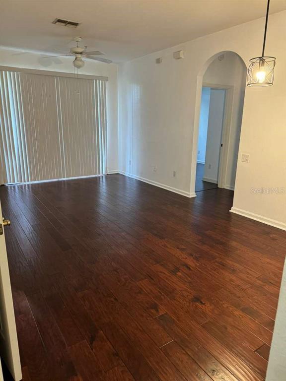 An empty room with dark wood flooring, a ceiling fan, and an arched doorway — 13524 TURTLE LOOP UNIT 617, ORLANDO, FL