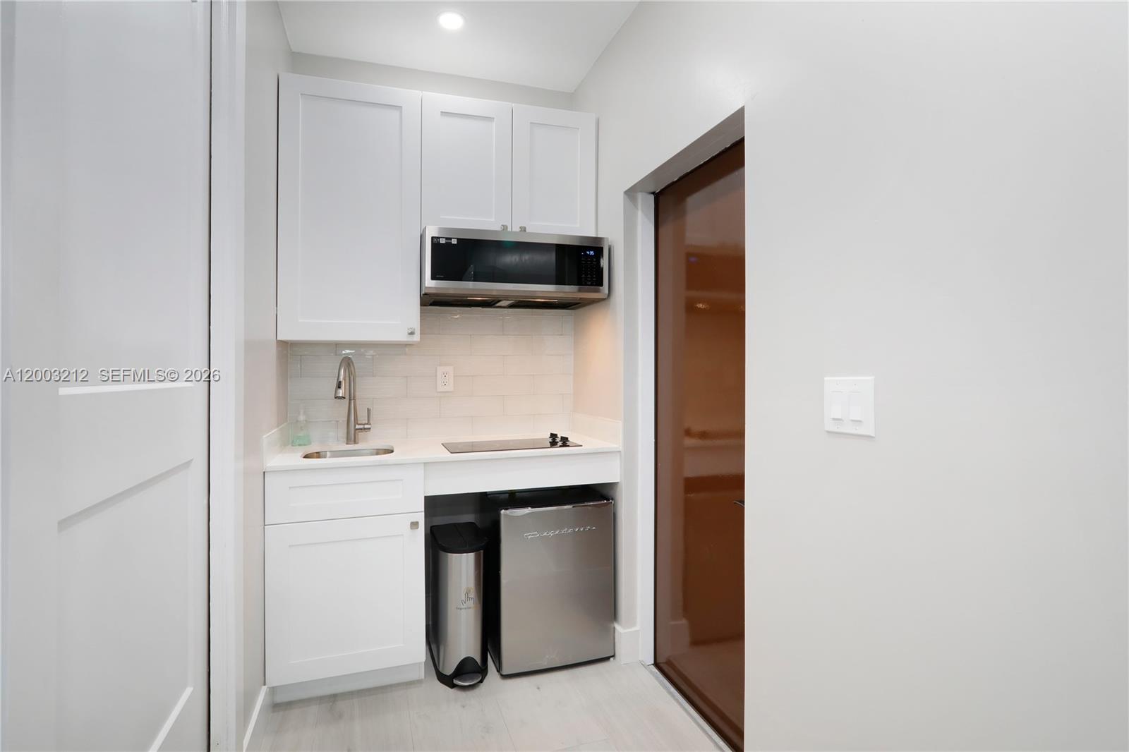 A small kitchenette features white cabinets, a stainless steel microwave, a sink, and a refrigerator — 2368 SW 21st St Side, Miami FL 33145, MIAMI, FL