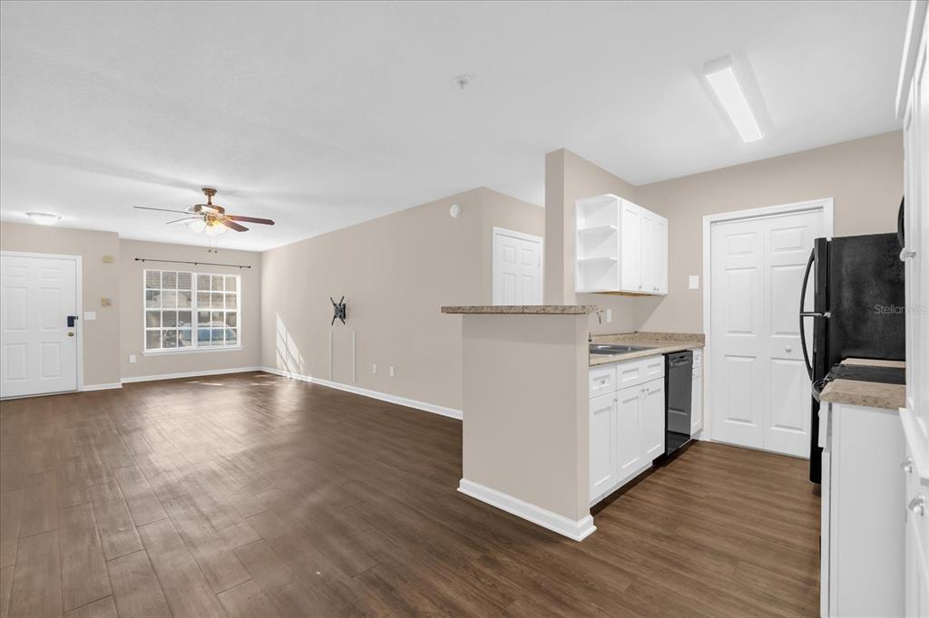 An open-concept living area features wood-look flooring, a ceiling fan, and a kitchen with white cabinets — 4316 S KIRKMAN ROAD UNIT 1611, ORLANDO, FL