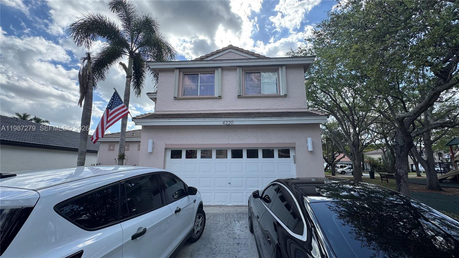 A two-story pink house with a two-car garage and two parked cars in the driveway — 4220 SW 153rd Ave, Miramar FL 33027, MIRAMAR, FL