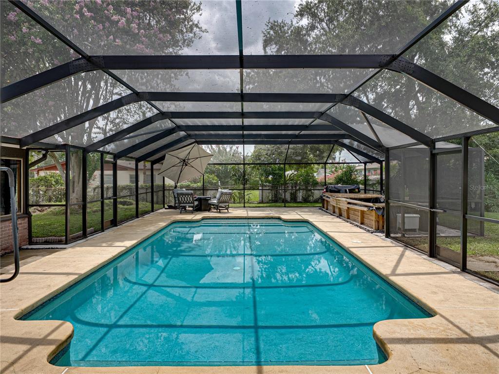 A rectangular swimming pool is enclosed by a screened-in lanai with a concrete deck — 609 W PIPKIN ROAD, LAKELAND, FL