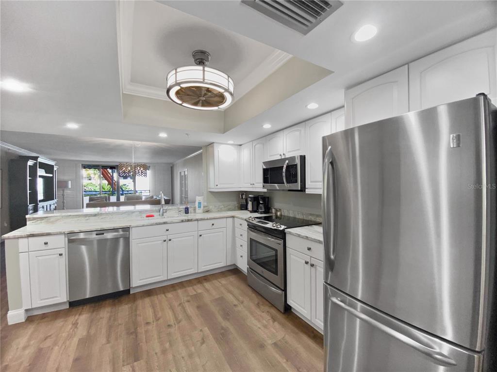 A kitchen with white cabinets, stainless steel appliances, and wood-look flooring — 1445 GULF OF MEXICO DRIVE UNIT 305, LONGBOAT KEY, FL