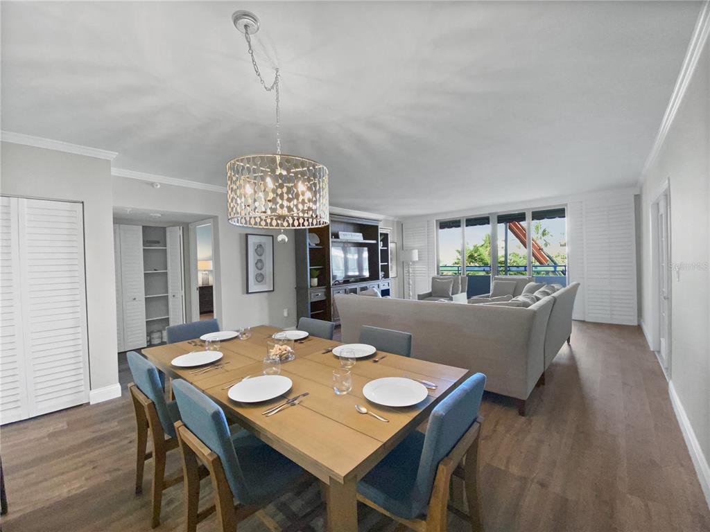 A dining area with a wooden table and blue chairs opens into a living room — 1445 GULF OF MEXICO DRIVE UNIT 305, LONGBOAT KEY, FL