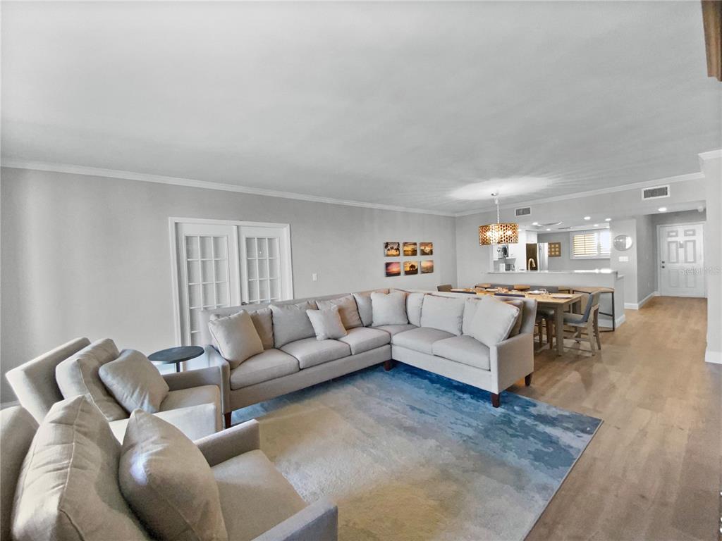 A living room with a large sectional sofa, area rug, and an adjacent dining area — 1445 GULF OF MEXICO DRIVE UNIT 305, LONGBOAT KEY, FL