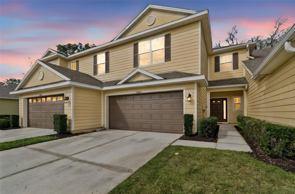 A two-story yellow house with a two-car garage and a front entrance under a portico — 20112 INDIAN ROSEWOOD DRIVE, TAMPA, FL