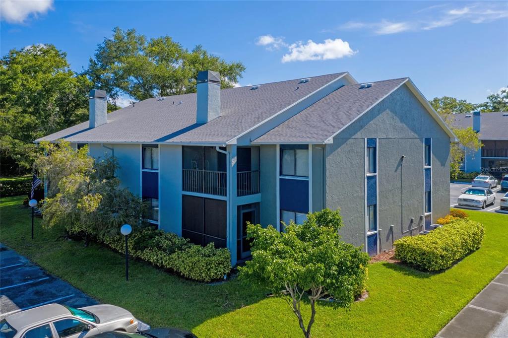 An exterior view of a two-story apartment building with a gray stucco facade and balconies — 13200 SW WILCOX ROAD UNIT 703, LARGO, FL