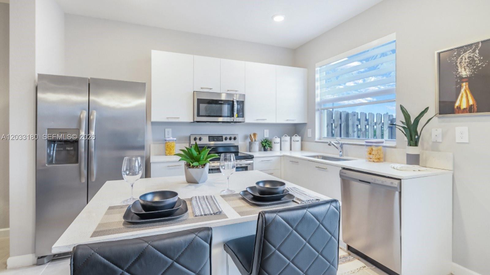 A modern kitchen features white cabinets, stainless steel appliances, and a central island with seating — 2592 SE 25 RD, Homestead FL 33035, HOMESTEAD, FL