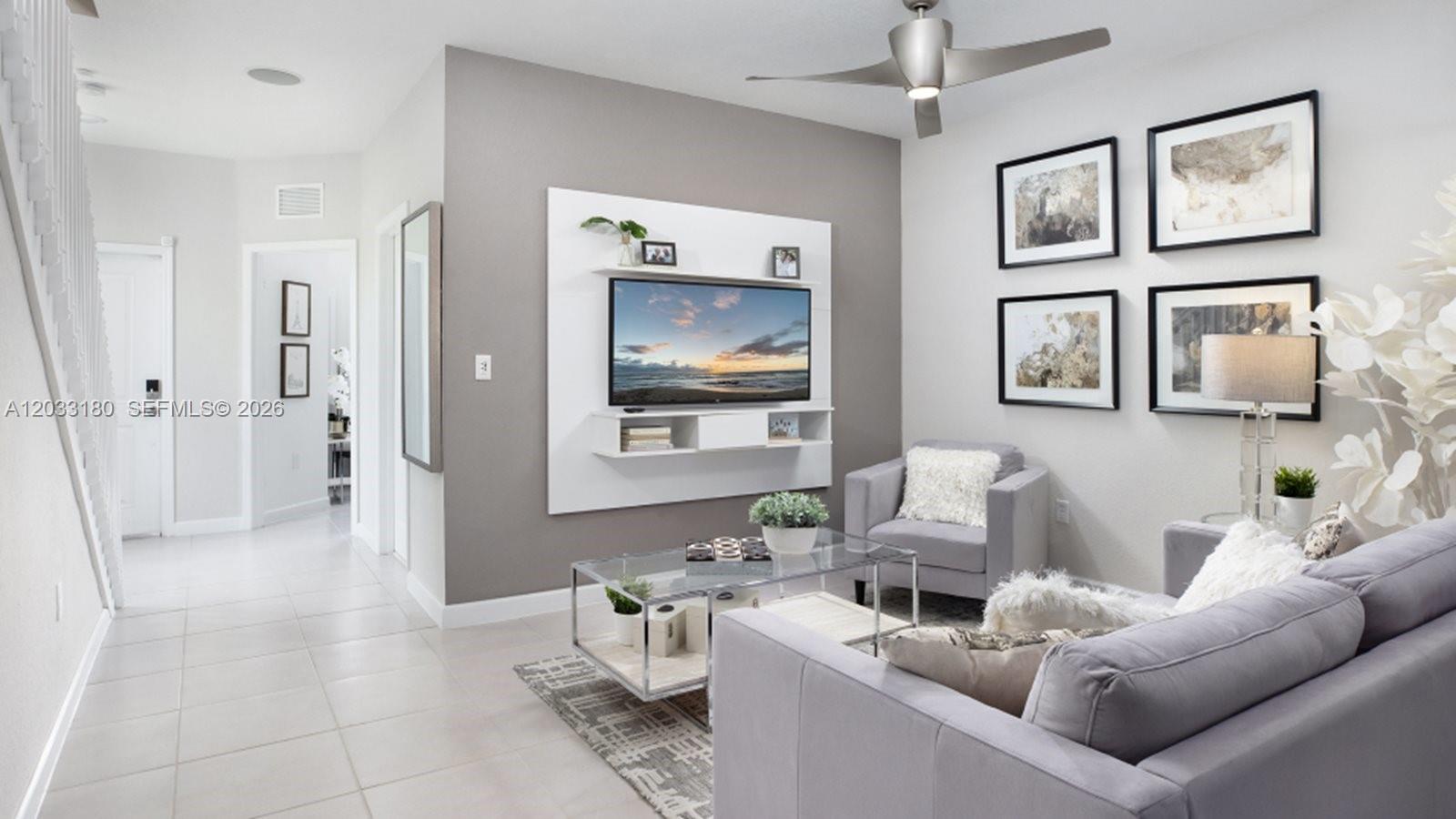 A living room features a wall-mounted television, gray sofa, armchair, and a glass coffee table — 2592 SE 25 RD, Homestead FL 33035, HOMESTEAD, FL