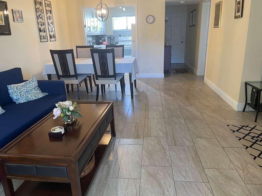 A living room with tile flooring, a blue sofa, and a dining area in the background — 2566 S Garden Drive # 108, Lake Worth FL 33461, LAKE WORTH, FL