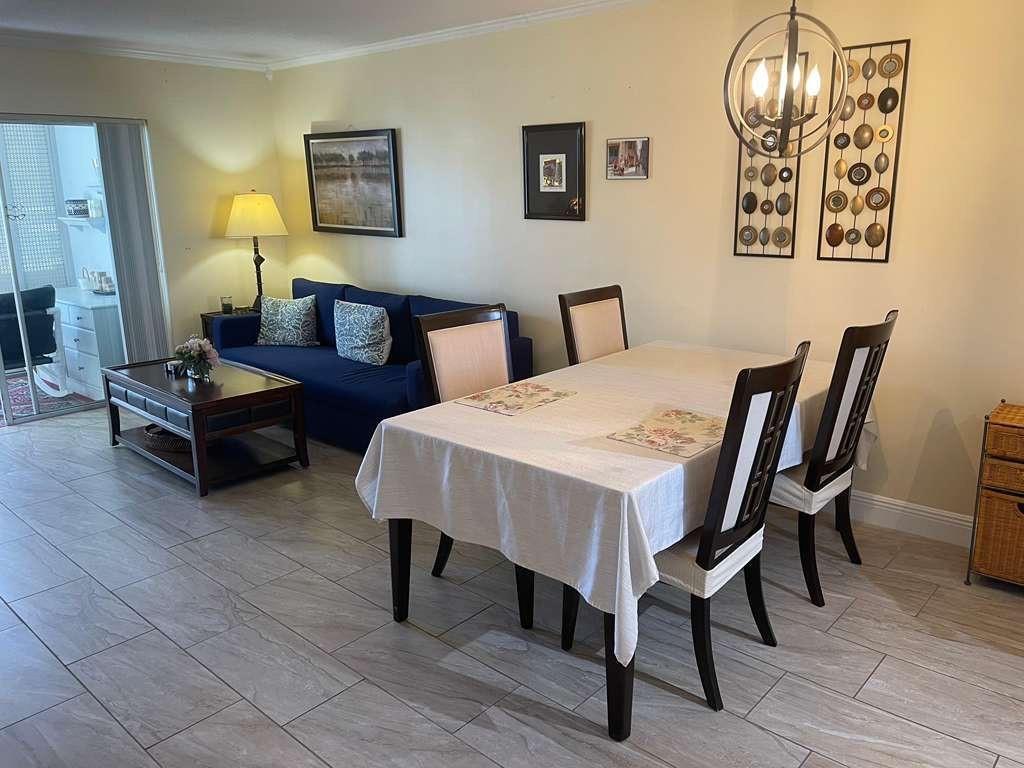 A dining area with a table and chairs sits adjacent to a living room sofa — 2566 S Garden Drive # 108, Lake Worth FL 33461, LAKE WORTH, FL
