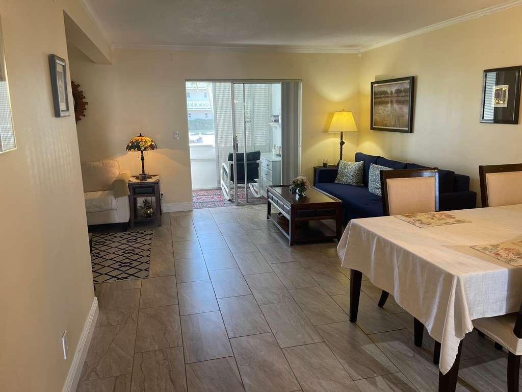 A living and dining area features tile flooring, a blue sofa, and a sliding glass door — 2566 S Garden Drive # 108, Lake Worth FL 33461, LAKE WORTH, FL