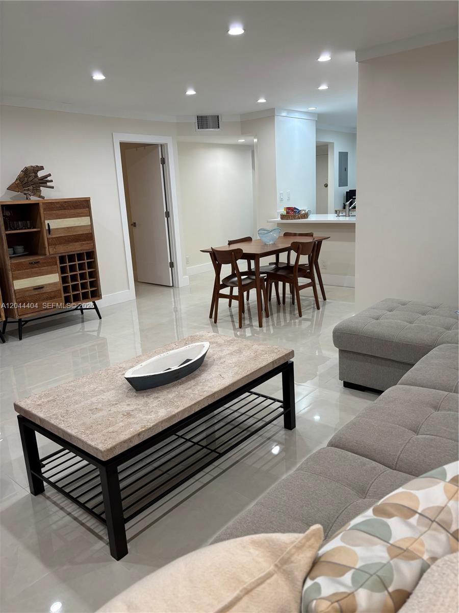 This living and dining area features tile flooring, a stone-topped coffee table, and wooden furniture — 3725 S Ocean Dr # 1225, Hollywood FL 33019, HOLLYWOOD, FL