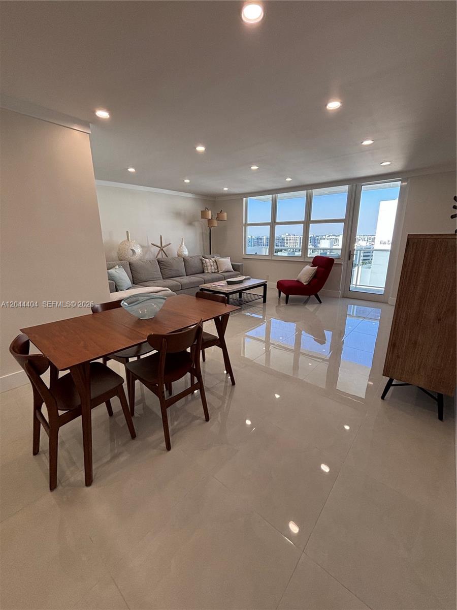 A dining and living area features tile floors, a wooden table, and large windows — 3725 S Ocean Dr # 1225, Hollywood FL 33019, HOLLYWOOD, FL