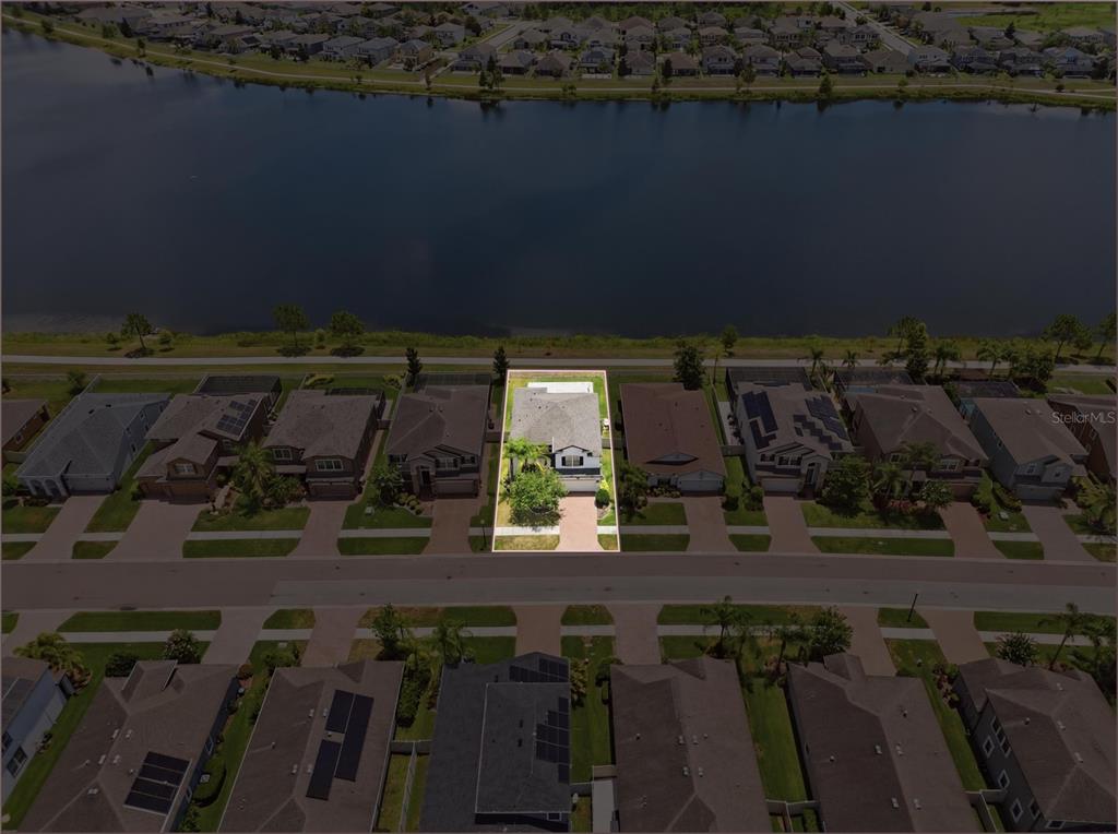 An aerial view shows a suburban neighborhood with houses bordering a large lake — 1806 NATURE VIEW DRIVE, LUTZ, FL