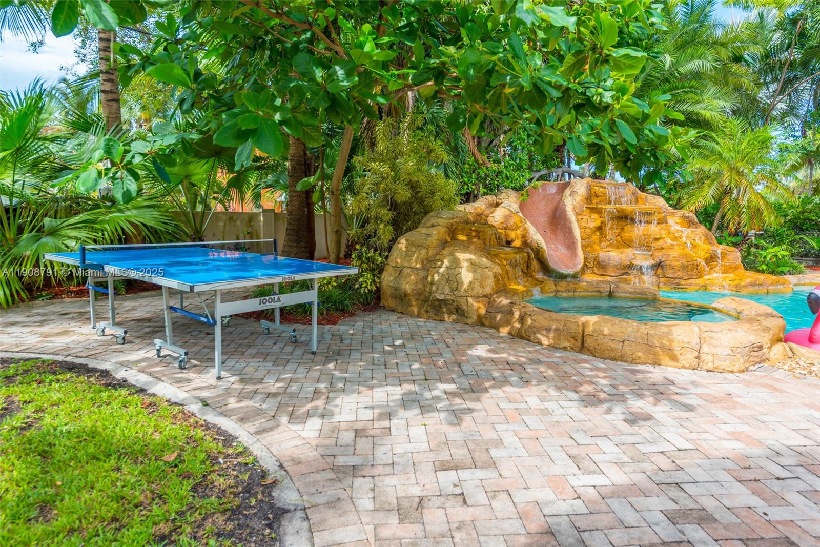 A blue ping pong table sits on a brick patio next to a rock waterfall — 1051 NE 89th St, Miami FL 33138, MIAMI, FL