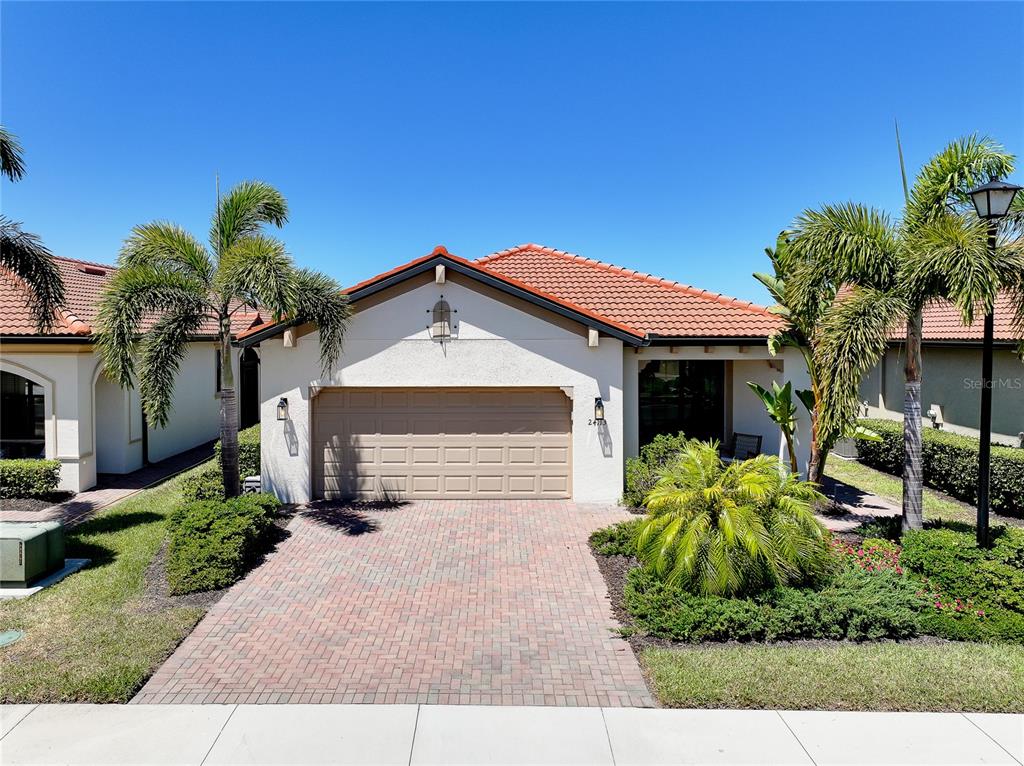 A single-story house with a tiled roof, a two-car garage, and palm trees in front — 24113 SPARTINA DRIVE, VENICE, FL