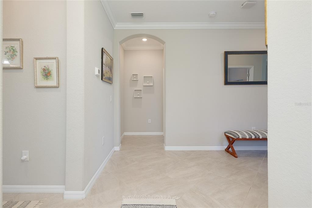 A neutral-toned entryway features tile flooring, an arched hallway, wall art, and a bench — 24113 SPARTINA DRIVE, VENICE, FL