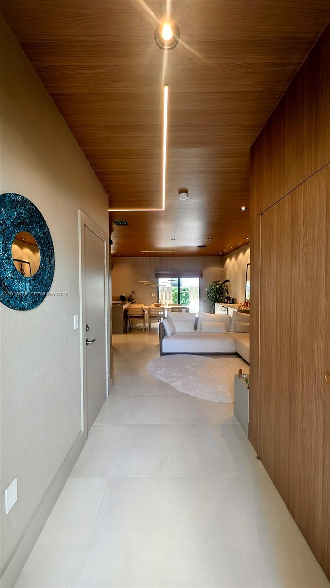 A hallway with light-colored tile flooring leads to an open-concept living and dining area — 20865 NE 7th Ct, Miami FL 33179, MIAMI, FL