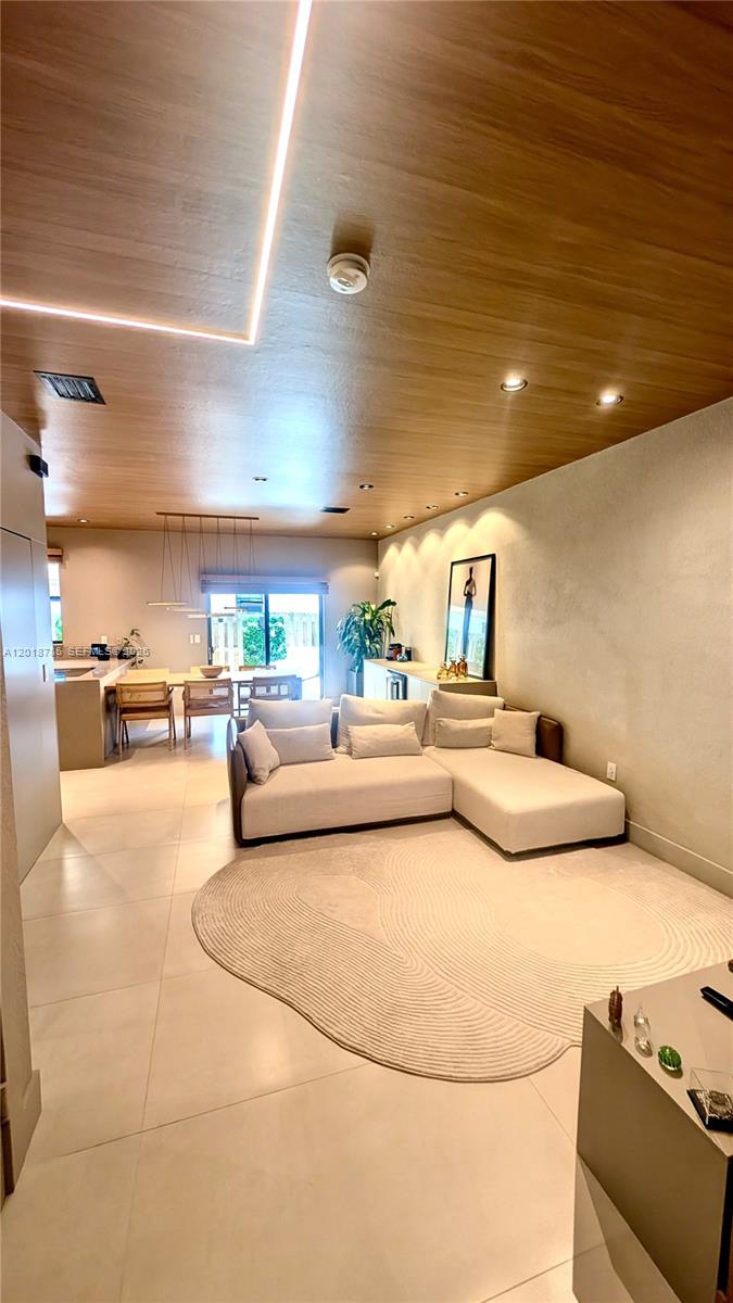 A modern living room features a beige sectional sofa, a curved rug, and wood-paneled ceilings — 20865 NE 7th Ct, Miami FL 33179, MIAMI, FL