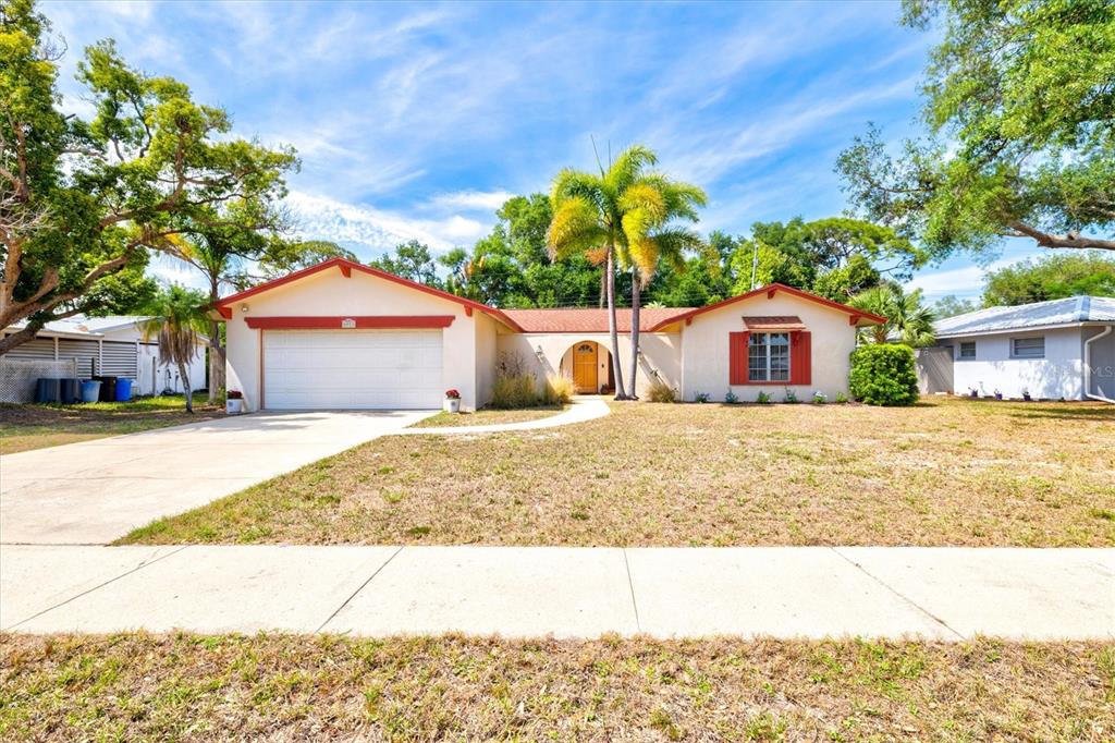 A single-story house with a white stucco exterior, red trim, and a palm tree — 6533 BOWLINE DRIVE, SARASOTA, FL