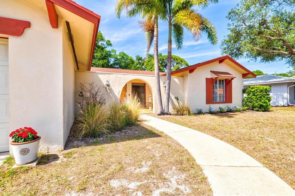 A single-story house with a stucco exterior, red trim, and a palm tree-lined walkway — 6533 BOWLINE DRIVE, SARASOTA, FL
